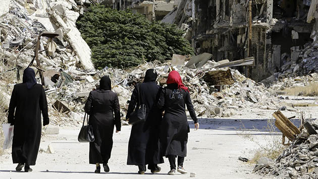 Mujeres sirias caminan junto a edificios destruidos en la ciudad de Homs. LOUAI BESHARA / AFP / GETTY