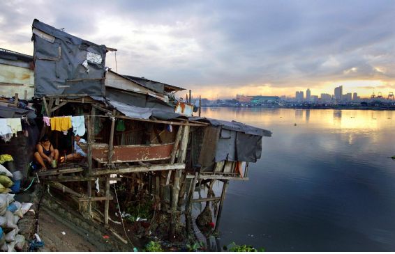 Personas que viven en una casa construida sobre pilotes al borde del agua, en un barrio marginal de Manila. © Robin Hammond / Panos 